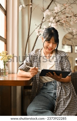 Portrait of satisfied female freelancer using digital tablet, studying remotely or browsing internet at home.