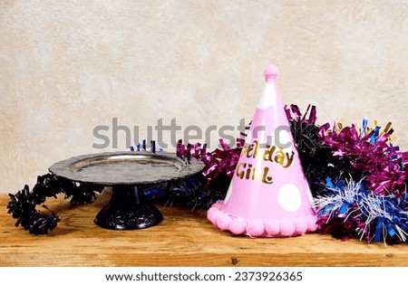 birthday girl party concept, empty stand cake and colorful tinsel on wood table