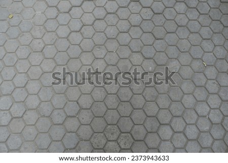 Surface of gray concrete pavement with honeycomb geometric pattern
