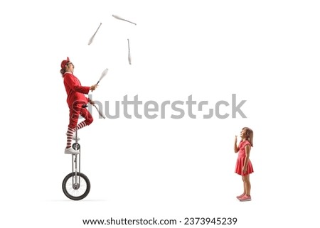 Excited girl watching an acrobat riding a giraffe unicycle and juggling isolated on white background