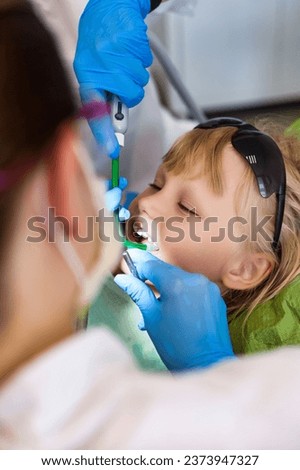 Dentist doctor having treating teeth little girl 5-6 year old at dental office. Dentist and assistant teeth doing treats kid girl in clinic. Concept of medical children dentistry. Copy ad text space