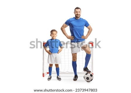 Man and a boy with a soccer ball wearing blue sport jerseys and standing in front of a mini goal isolated on white background