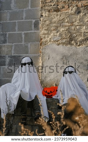 Funny Halloween Kid Concept, 2 little kids with white dressed costume halloween ghost scary with sunglasses, Ghost costume for Halloween concept.  A ghost of a child under a white sheet.