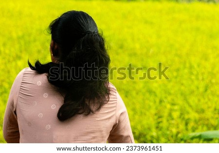A woman is sitting and looking at the farmland below.