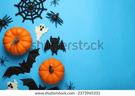 Flat lay composition with bats, pumpkins, ghosts and spiders on light blue background, space for text. Halloween celebration