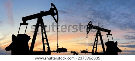 Oil pump jack. Oil industry equipment rig silhouette against sunset sky clouds background