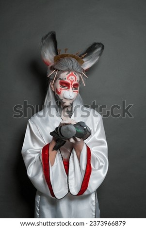 Fashion woman with Halloween makeup holding bird pigeon, studio portrait