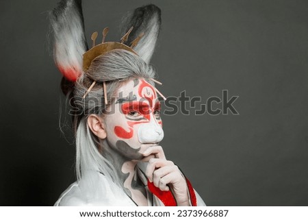Сunning woman in animal mask closeup on gray background. Halloween, Carnival and Cosplay concept