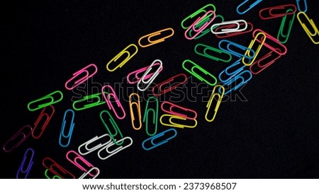Colorful paper clips isolated on black background.