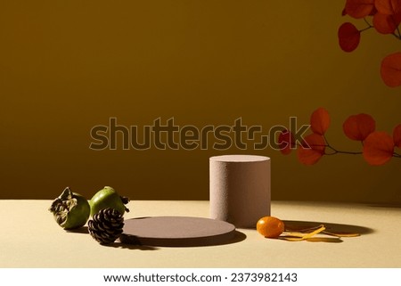 Autumn concept for advertising cosmetic product with blank space. Two brown podiums decorated with green persimmon and cherry tomato and autumn leaves on brown background