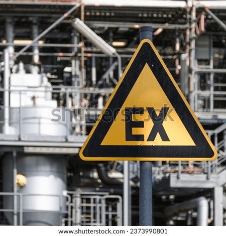 Warning sign "explosive atmosphere" - the word "EX" on a yellow triangle with black borders - in front of a blurred industrial background Royalty-Free Stock Photo #2373990801