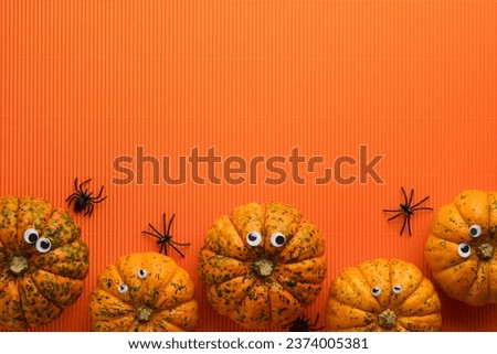 Halloween holiday background. Orange pumpkin, bat with funny eyes, spider, spider web, old leaves and branches from scary forest on orange background. Happy halloween card. Autumn decoration. Top view