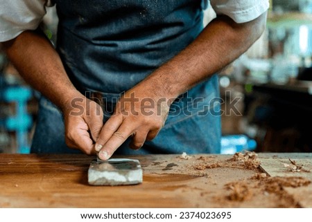 A woodworker is shown sharpening a chisel on a whetstone. The footage captures the essential steps of the sharpening process, and is ideal for use in educational or instructional materials. Royalty-Free Stock Photo #2374023695