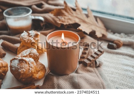 Burning candle with the smell of chocolate and cinnamon in a cozy home interior.