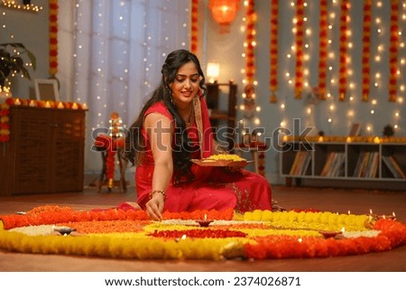 happy young Indian woman preparing diwali flower rangoli on floor for pooja or ritual at home - concept of festive celebration, special occasion and traditional culture or wear Royalty-Free Stock Photo #2374026871
