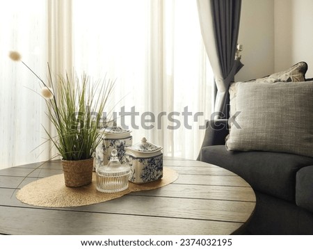 Fresh flowers in a white vase placed on a small table in a bright room interior with jars of food on the background of a sunny window