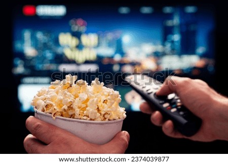 Tv movie night with family. Stream VOD platform. Popcorn and remote control. Video entertainment and snack. Play online film on television. On demand service. Streaming series on digital device. Royalty-Free Stock Photo #2374039877
