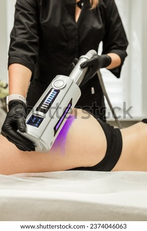 Hardware figure correction. Machine cosmetology. Beautiful woman having cavitation, procedure removing cellulite on her buttocks. Royalty-Free Stock Photo #2374046063