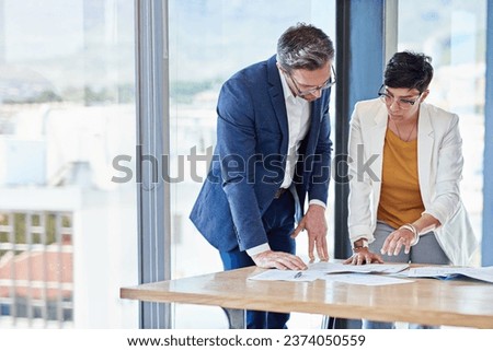Developing new strategies. Shot of two colleagues going over paperwork together in an office. Royalty-Free Stock Photo #2374050559