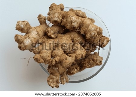 Zingiber officinale rhizome or ground ginger root, inside a transparent bowl. Isolated in white background.