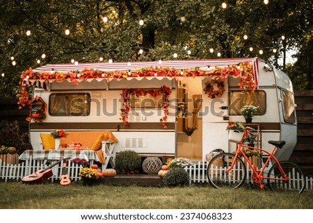 Camping season is autumn. Photo studio. Trailer against the backdrop of the forest. A bicycle in front of a trailer. light bulbs glow