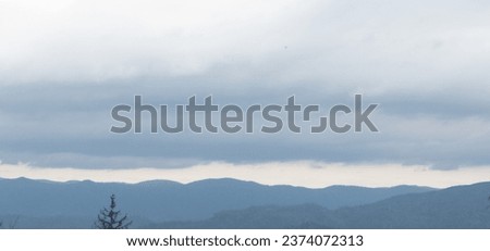 Autumn brings overcast skies adorned with gray stratus clouds, hinting at impending rain. This full-screen view provides ample space for text or design elements, making it perfect for various projects Royalty-Free Stock Photo #2374072313