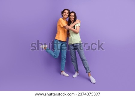 Full body photo two lesbians couple lovers brunettes cuddles together denim jeans basic t shirt advert isolated on purple color background Royalty-Free Stock Photo #2374075397