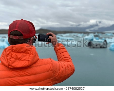 Tourist make a photo by phone. Icebergs in Jokulsarlon glacier lagoon. Lake in Vatnajokull Nalional park Iceland. Popular attraction. 