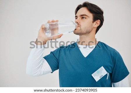 Surgeon, man drinking water in bottle and health, wellness or body nutrition in studio isolated on white background in hospital. Medical professional, hydration and liquid of thirsty nurse on break
