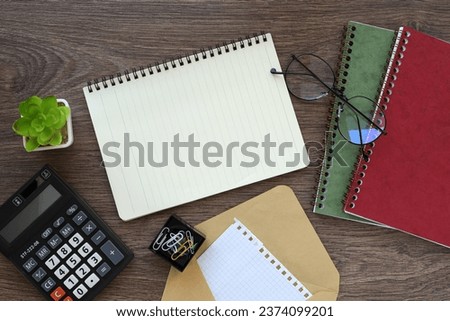 notebook on a dark wooden background, spiral notepad on the table near glasses and calculator