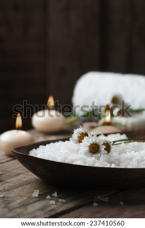 Spa concept with daisy, white salt and candles on wooden background, selective focus