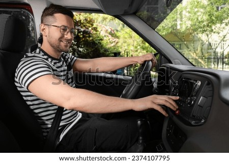 Choosing favorite radio. Handsome man pressing button on vehicle audio in car Royalty-Free Stock Photo #2374107795