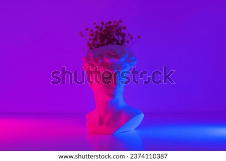 Plaster antique David's statue head with flowers inside pink and blue colored neon light. 3d trendy collage in magazine style. Contemporary art. Modern creative design Royalty-Free Stock Photo #2374110387