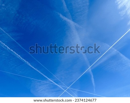 Airplanes leaving diagonal contrails on a clear blue sky Royalty-Free Stock Photo #2374124677