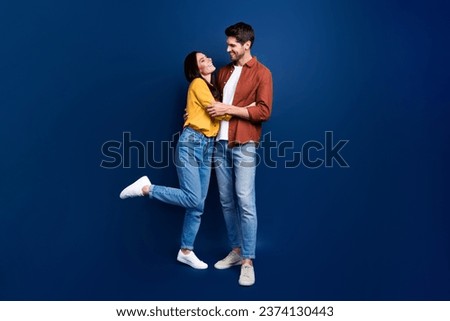 Full length photo of two cheerful idyllic partners hug look each other isolated on dark blue color background