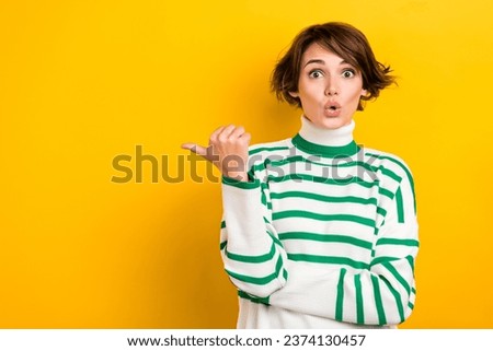 Photo of shiny impressed girl dressed striped sweater showing thumb empty space isolated yellow color background