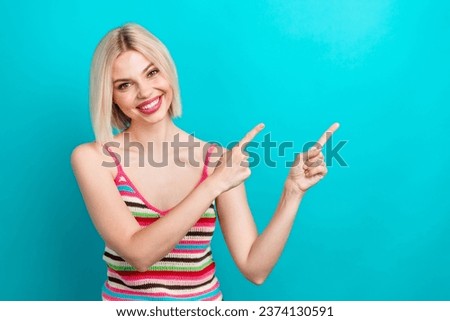 Photo portrait of attractive young woman finger point empty space dressed stylish striped clothes isolated on aquamarine color background