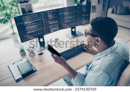 Side view photo of busy coder hacker young guy working office trying input his mobile app to smartphone workshop workspace indoors