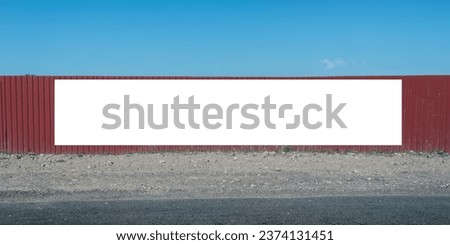 Empty white long banner mounted on red metal fence of industrial zone outdoor front view