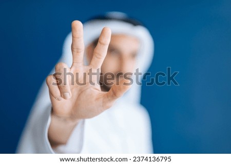 handsome man with dish dasha working in his business office of Dubai. Portraits of a successful businessman in traditional emirates white dress. Concept about middle eastern cultures. Royalty-Free Stock Photo #2374136795