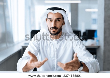 handsome man with dish dasha working in his business office of Dubai. Portraits of a successful businessman in traditional emirates white dress. Concept about middle eastern cultures. Royalty-Free Stock Photo #2374136801