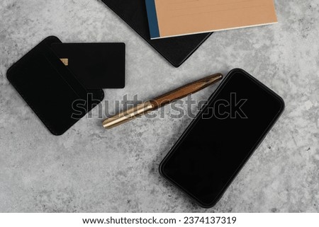 Stylish minimalist mockup with credit card, planner, phone and pen on grey background with copyspace. Aesthetic minimal office desk table mockup. Flat lay, top view.