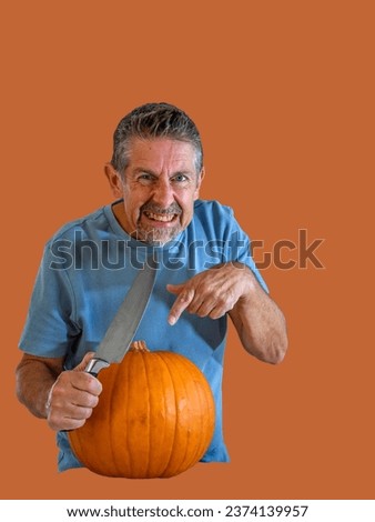 Isolated pumpkin picture, Man holds a sharp knife with a menacing smile, grimace, he's about to carve the squash for his recipe in the kitchen. Bright blue and orange capture with copy space.