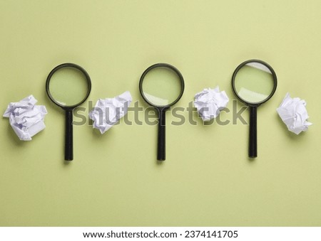 Magnifiers with crumpled paper balls on a green background. Business concept