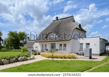 Modern thatch roofed house with heat pump heating system Royalty-Free Stock Photo #2374156521