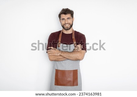 Cheerful man barista barman in apron posing with crossed folded arms, smiling at camera isolated on white background.. Small business startup concept Royalty-Free Stock Photo #2374163981