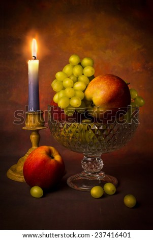 Still life of red apples and green grapes in a glass vase on a dark background