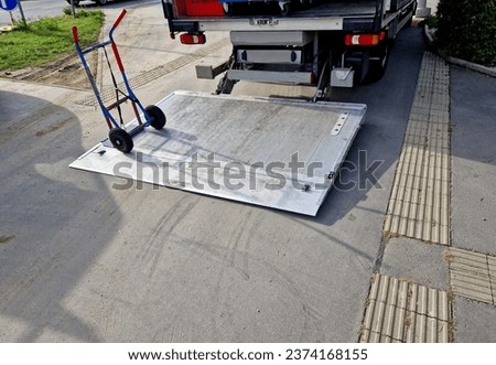 is a very robust medium-duty column lift with a long foldable platform, suitable for handling pallets with a pallet jack. The folded platform can be lowered below the vehicle floor, allow, elevator  Royalty-Free Stock Photo #2374168155