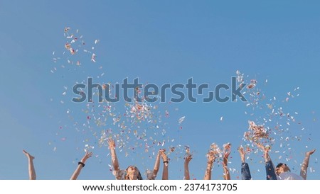 Tossing colorful paper confetti from the hands of young people. Royalty-Free Stock Photo #2374173705