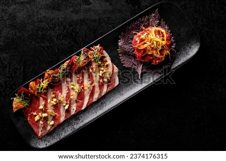 Smoked duck breast fillet sliced and tartare beef on plate in restaurant.